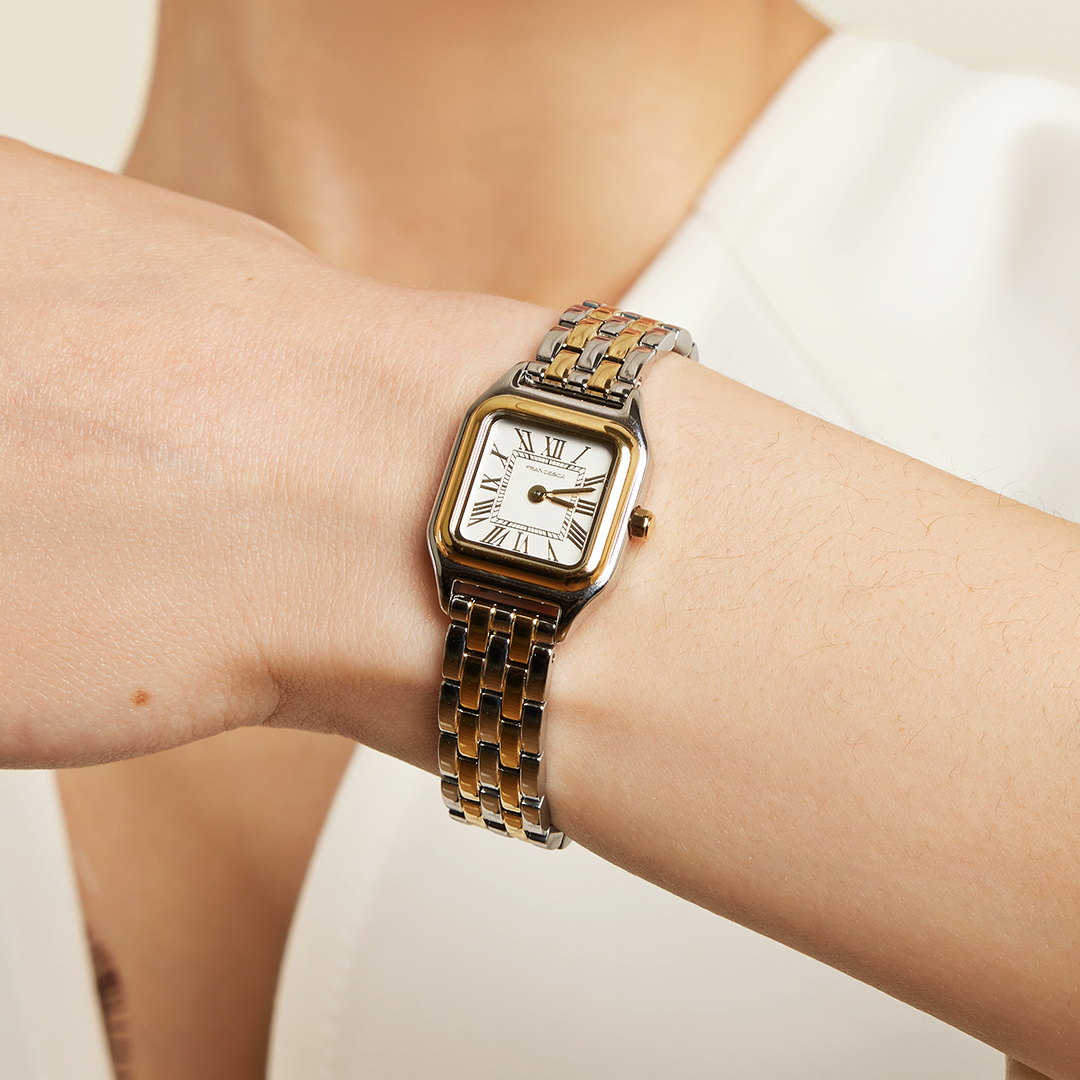 A two-toned Louis Watch with a link bracelet and a square face featuring Roman numerals worn on the wrist