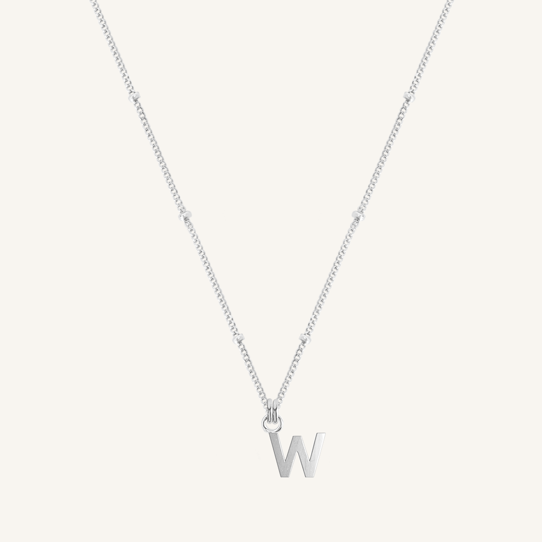 Silver necklace with a 'W' pendant on a light gray background