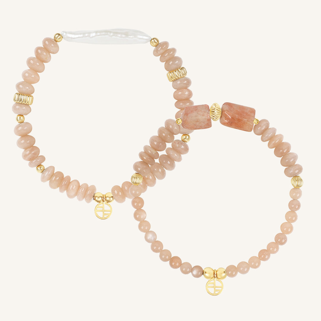 Set of two pink beaded bracelets with gold accents on a white background