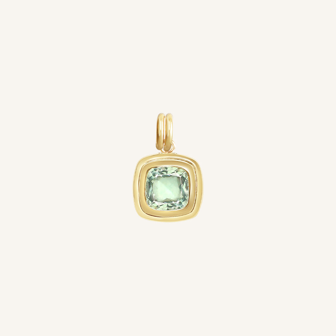 Gold pendant with a green gemstone on a white background