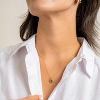 Gold pendant with a green gemstone on a white background