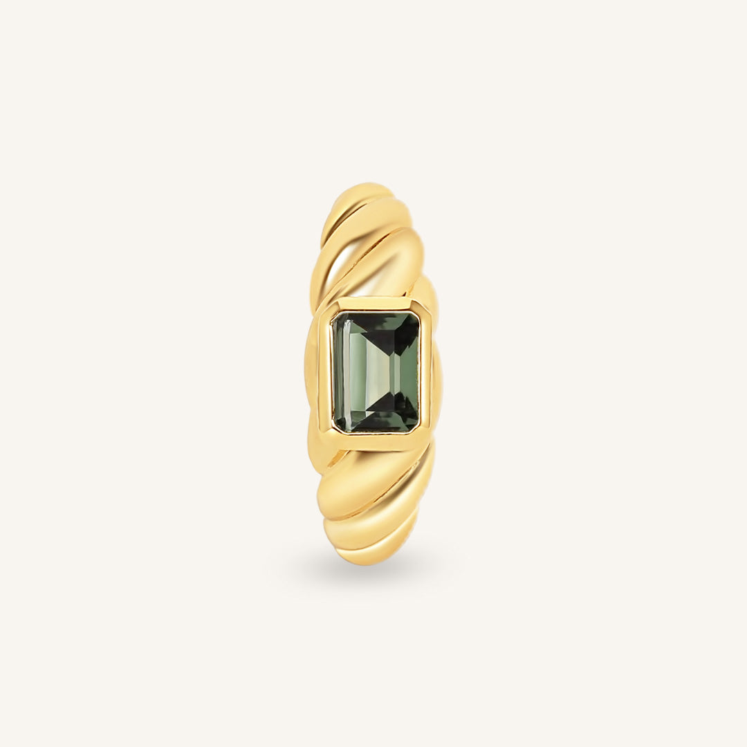 Gold ring with a green gemstone on a white background