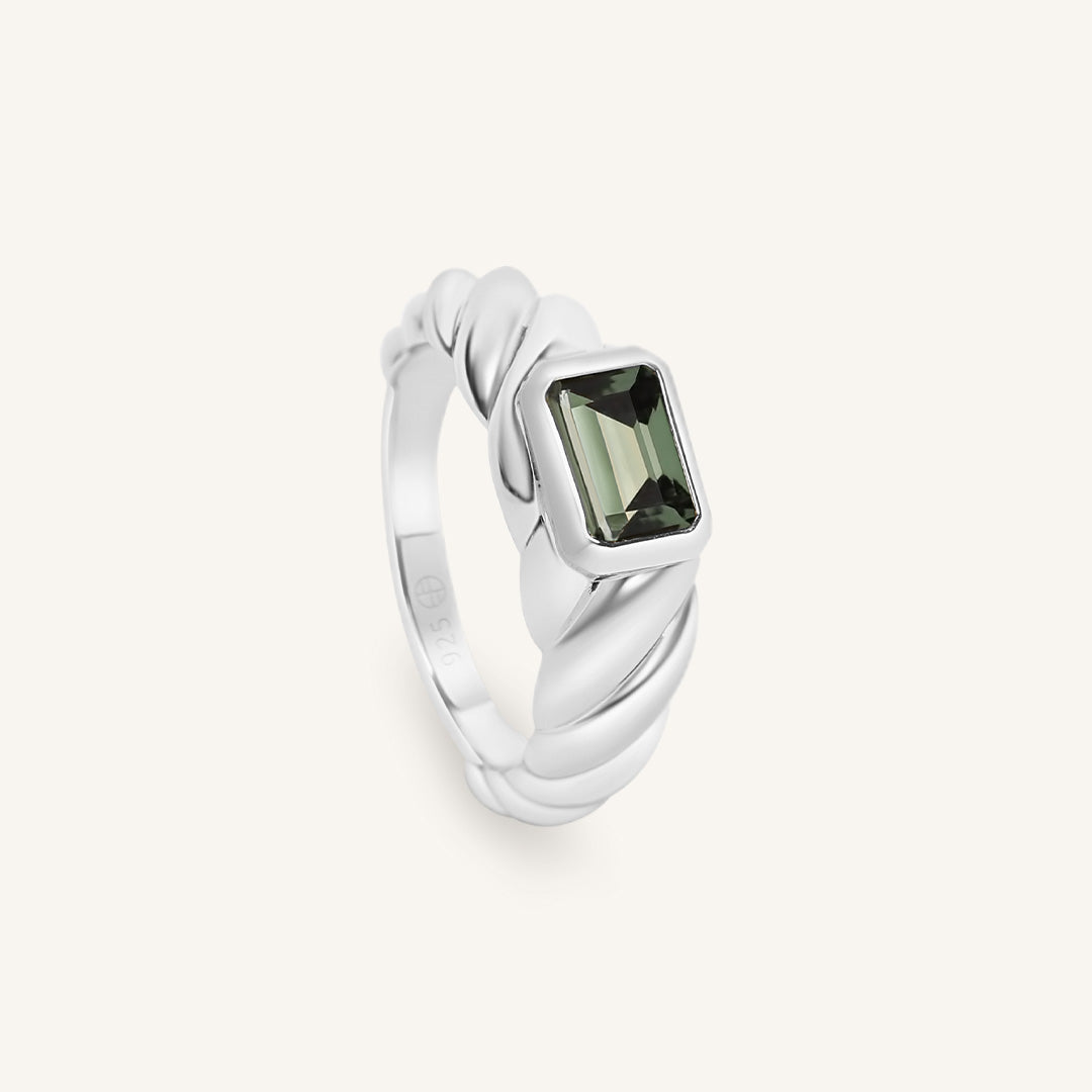 Silver ring with a green gemstone on a white background