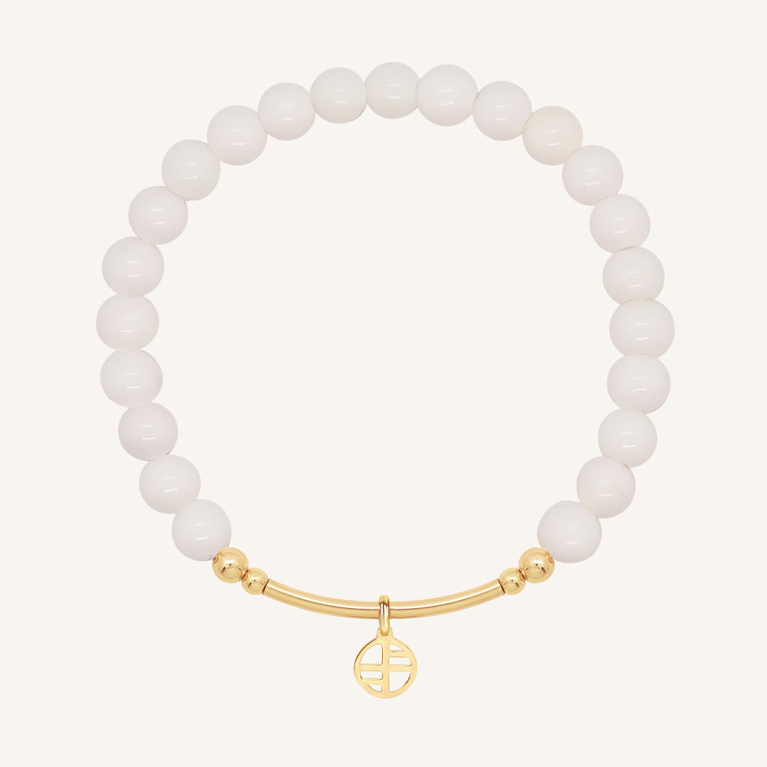 White beaded bracelet with a gold clasp on a white background
