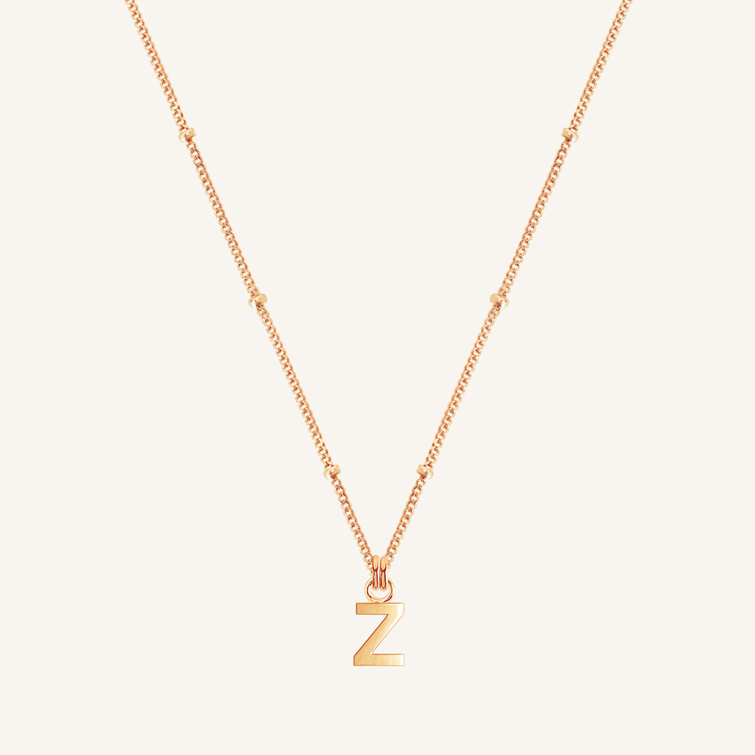 Gold necklace with a 'Z' pendant on a light beige background