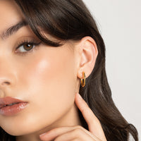 A pair of gold-tone hoop earrings on a white background