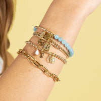 A rose-colored charm in the shape of a keylock with intricate patterns.