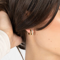 A pair of gold-colored hoop earrings with a huggie design, featuring a layered look.