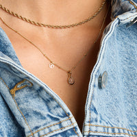 a gold charm with a tear-drop shaped rose quartz stone 