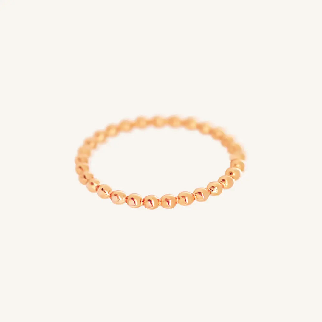 A rose gold coloured stacking ring with a simple, elegant design featuring small, uniform beads around its circumference.
