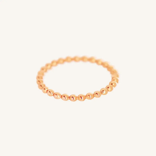 A rose gold coloured stacking ring with a simple, elegant design featuring small, uniform beads around its circumference.