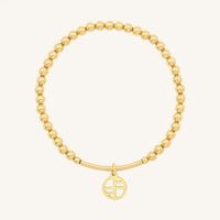 A gold-tone charm bracelet with 4mm beads and a charm pendant hanging in the center.