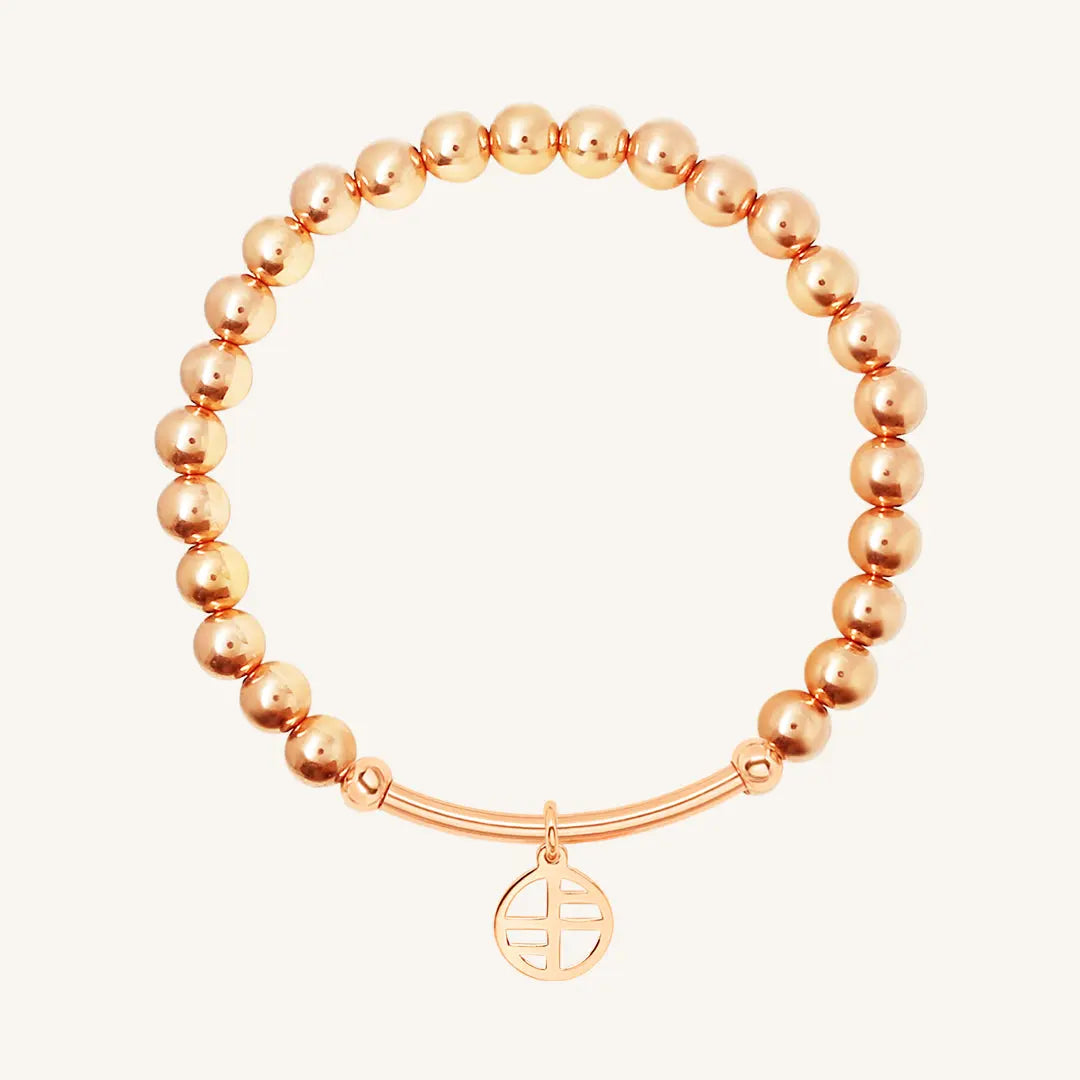 A ROSE-tone charm bracelet with a beaded design and a circular charm hanging from a bar.