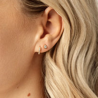 A pair of teardrop-shaped cubic zirconia stud earrings set in gold-tone settings.